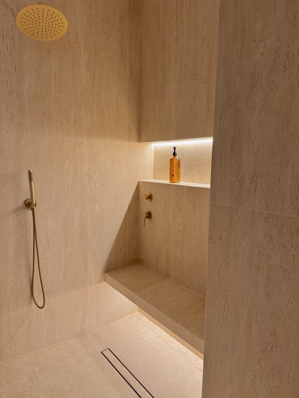 Rain shower with travertine walls and brass fixtures