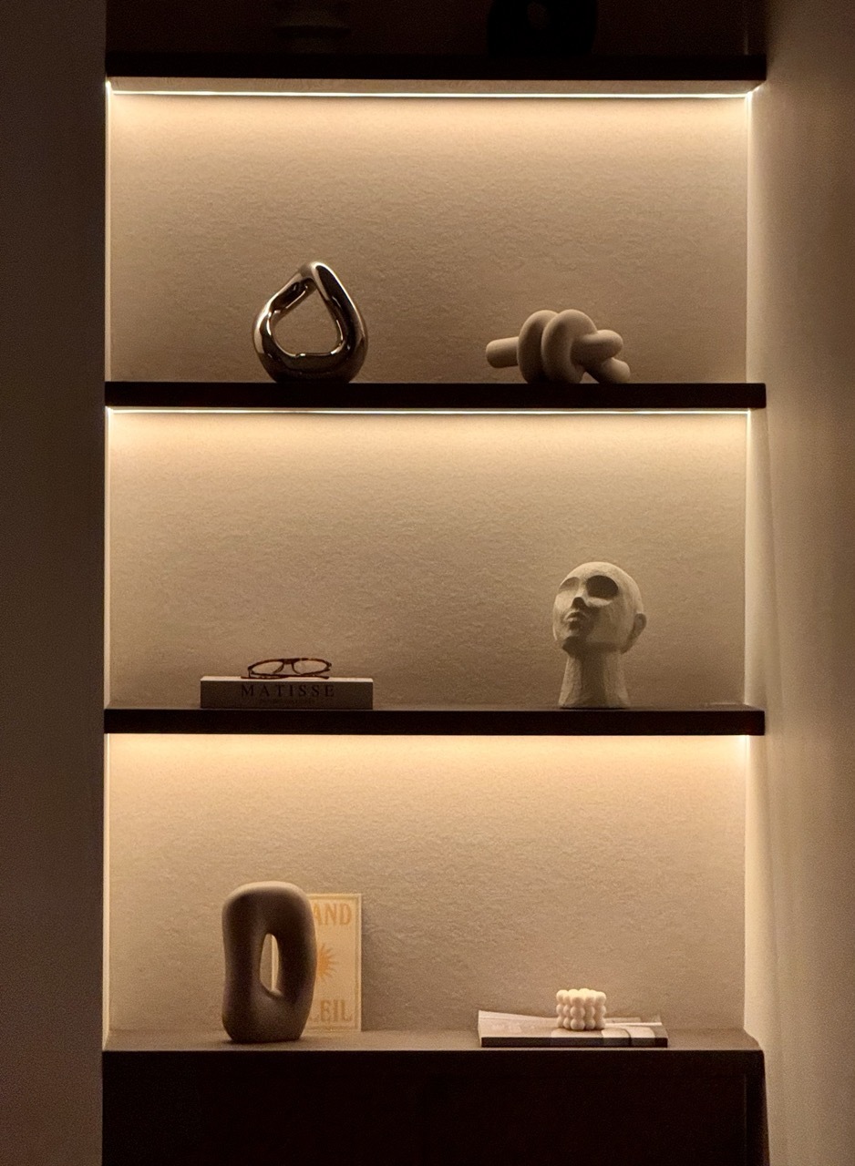 Illuminated built-in shelves with sculptural objects, warm evening lighting