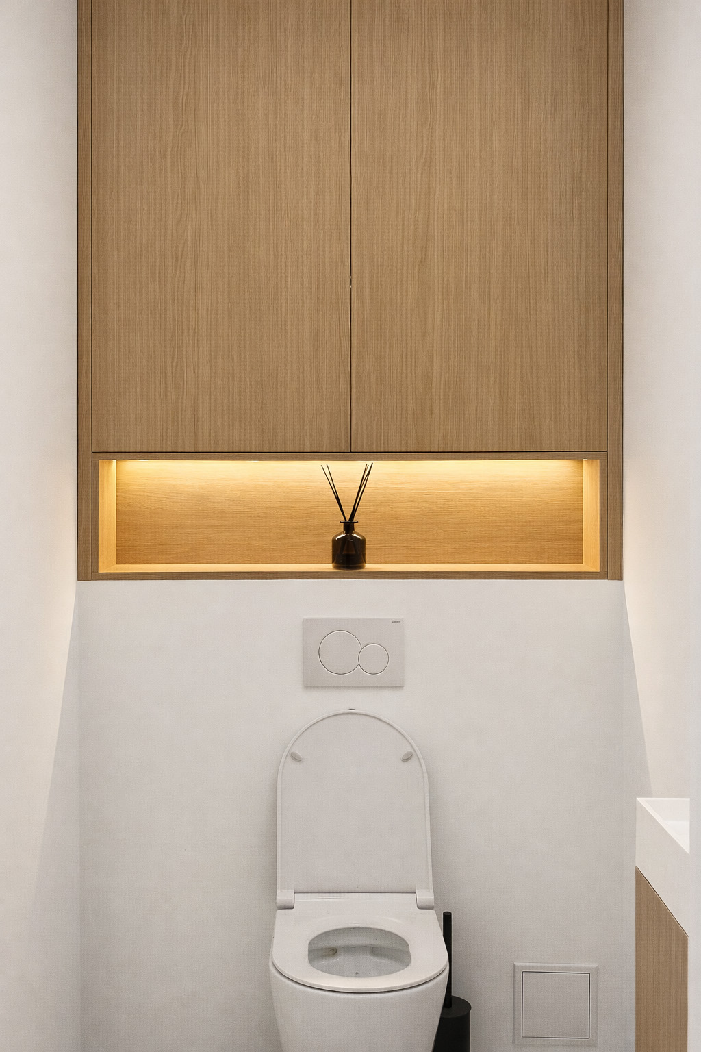 Separate guest toilet with oak cabinetry and ambient niche lighting